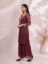 Woman wearing a maroon embroidered kurta with flowing sharara pants, featuring gold neckline and cuff details.