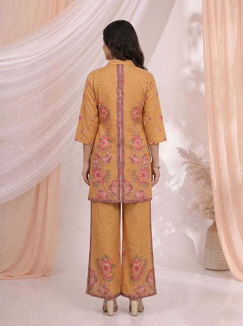 Woman wearing an ochre yellow kurta and palazzo set with a vibrant floral print.