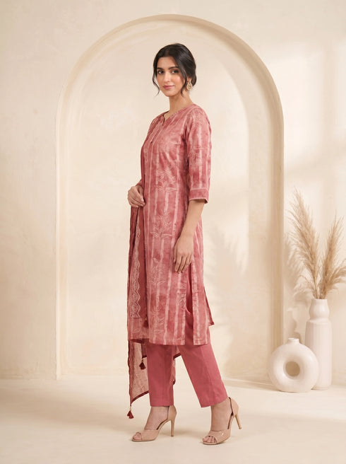 Woman wearing a rose pink printed kurti set with a dupatta, featuring leaf motifs and striped patterns.