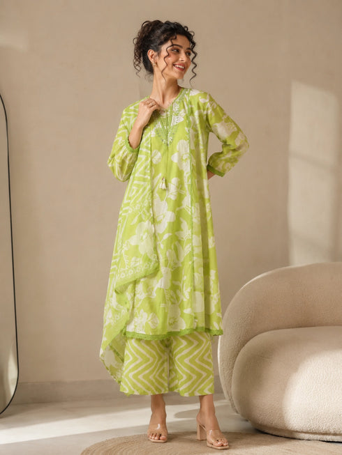 Woman wearing a lime green printed kurti and chevron patterned pants, sitting on a cream sofa.