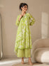 Woman wearing a lime green printed kurti and chevron patterned pants, sitting on a cream sofa.