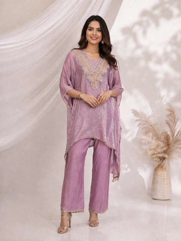 Woman wearing a shimmering purple kaftan top and matching pants, featuring an embellished neckline and gold heels.