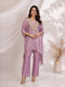 Woman wearing a shimmering purple kaftan top and matching pants, featuring an embellished neckline and gold heels.