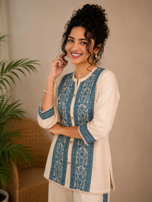 Woman wearing a cream kurta with blue paisley print, showcasing intricate embroidery and a band collar neckline.