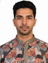Man wearing a multi-color floral print kurta with an embellished neckline and cream churidar pants.