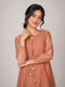 Woman wearing a peach embroidered kurta with gold tassels and a tie-neck detail.