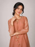 Woman wearing a peach embroidered kurta with gold tassels and a tie-neck detail.