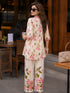 Woman wearing a pink floral print Co ord set, sitting at a table.