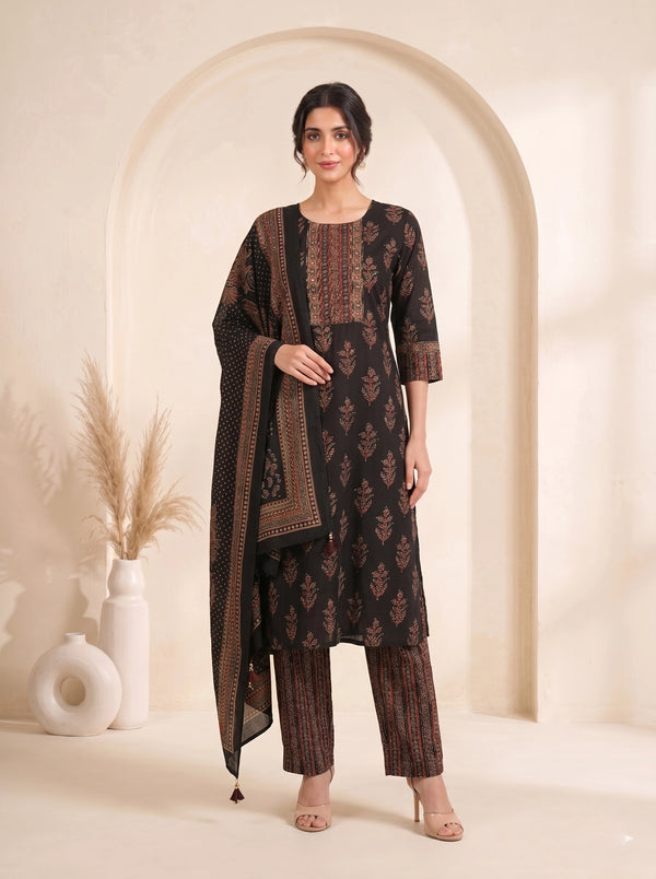 Woman wearing a black printed kurti set with a dupatta, featuring intricate red and gold patterns.