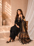 Woman wearing a black embroidered kurti and palazzo set with a colorful printed dupatta, seated on a chair.
