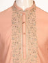 Man wearing a peach silk Kurta Pajama with intricate embroidery on the neckline and cream churidar pants.