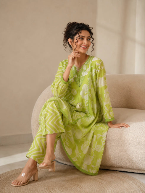 Woman wearing a lime green printed kurti and chevron patterned pants, sitting on a cream sofa.