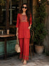 Woman wearing a rust-colored embroidered Co ord set, sitting at a cafe table.