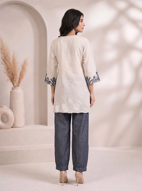 Woman wearing a beige embroidered V-neck kurta with dark blue palazzo pants, styled for a casual occasion.