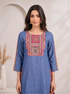 Woman wearing a blue embroidered kurta and matching wide-leg pants with a geometric border, styled with nude heels.