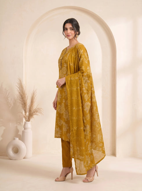 Woman wearing a mustard yellow floral print cotton kurti set with a dupatta and beige heels.