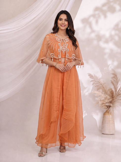Woman wearing an orange embellished cape and flowing pants set, perfect for festive occasions.