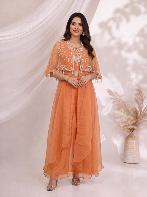Woman wearing an orange embellished cape and flowing pants set, perfect for festive occasions.