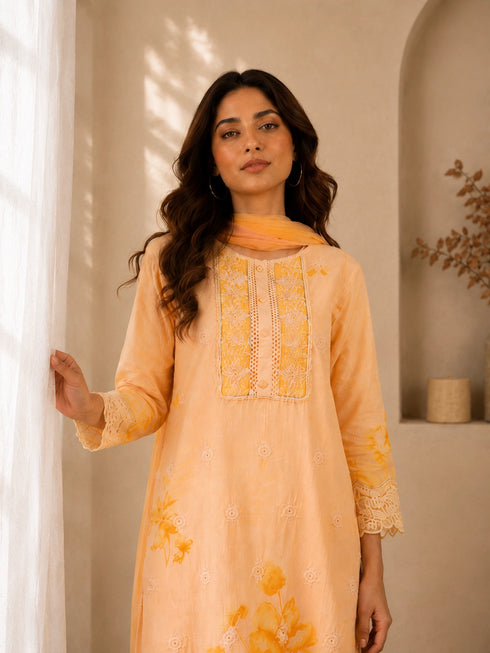 Woman wearing a yellow floral embroidered Kurti Set with lace trim and matching dupatta.
