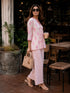 Woman wearing a pink floral print cotton kurta and matching pants, sitting at a table.