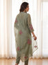 Woman wearing a green floral embroidered kurta set with a sheer dupatta and gold heels.