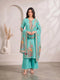 Woman wearing a teal kurti set with floral prints and matching palazzo pants, draped with a dupatta.