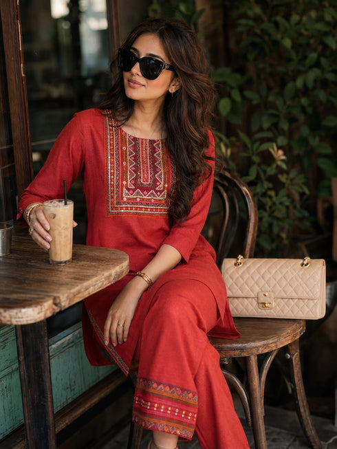 Woman wearing a rust-colored embroidered Co ord set, sitting at a cafe table.
