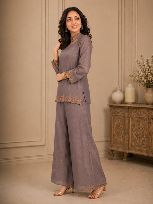 Woman wearing a pink embroidered choker neck Sharara with floral details on sleeves and hem.
