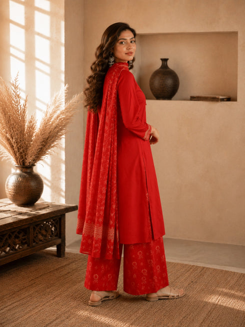 Woman wearing a rust-colored printed cotton kurti and pants set with intricate border details.