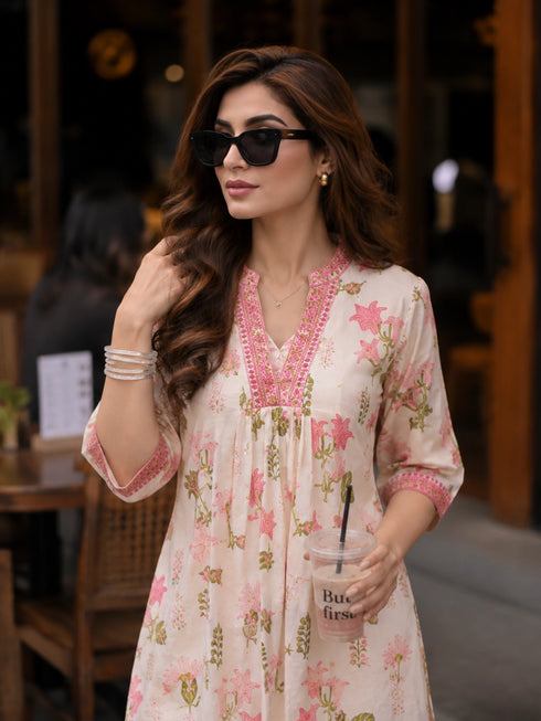 Woman wearing a pink floral print Co ord set, sitting at a table.