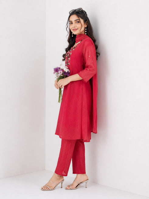 Woman wearing a Rani red Sharara with a geometric print yoke and matching dupatta, styled with pearl earrings.