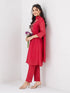Woman wearing a Rani red Sharara with a geometric print yoke and matching dupatta, styled with pearl earrings.
