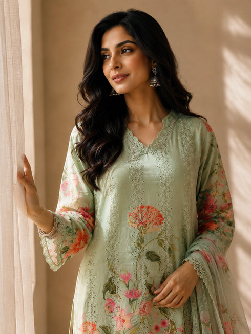 A woman models a green floral embroidered Kurti Set with matching pants and a dupatta, featuring delicate lace trim.