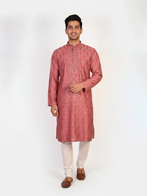 Man wearing a rose embroidered Kurta Pajama with white pants and brown jutti shoes.