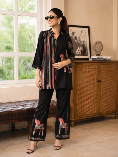 Woman wearing a cream and black striped pajama set with horse prints, sitting on a bench.