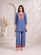 Woman wearing a blue embroidered kurta and matching wide-leg pants with a geometric border, styled with nude heels.