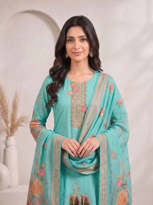Woman wearing a teal kurti set with floral prints and matching palazzo pants, draped with a dupatta.