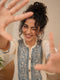 Woman wearing a cream kurta with blue paisley print, showcasing intricate embroidery and a band collar neckline.