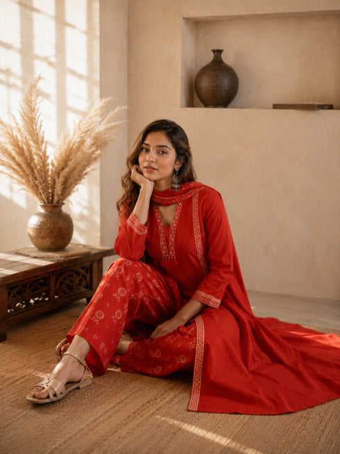 Woman wearing a rust-colored printed cotton kurti and pants set with intricate border details.