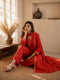 Woman wearing a rust-colored printed cotton kurti and pants set with intricate border details.