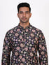 Man wearing a dark multi-color floral print kurta and white churidar pants, traditional ethnic wear.