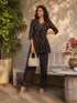 Woman wearing a black paisley print kurta and matching pants, sitting on a bench.