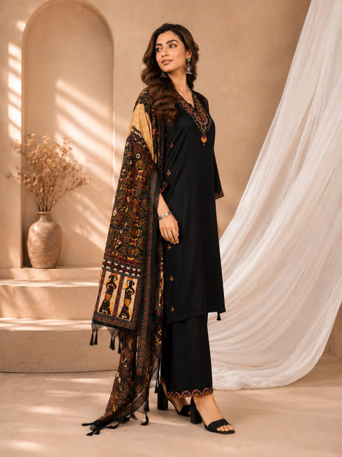 Woman wearing a black embroidered kurti and palazzo set with a colorful printed dupatta, seated on a chair.