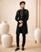 Man wearing a stylish black Indo-Western suit, showcasing intricate details and a modern fit.