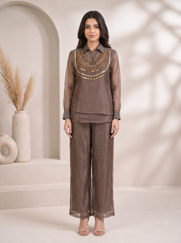 Woman wearing a grey sheer co-ord set with a detailed gold beaded and sequined neckline and wide-leg pants.