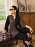 Woman wearing a cream and black striped pajama set with horse prints, sitting on a bench.