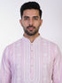 Man wearing a pink chikankari kurta with white churidar pants and brown embellished juttis.