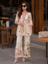 Woman wearing a pink floral print Co ord set, sitting at a table.