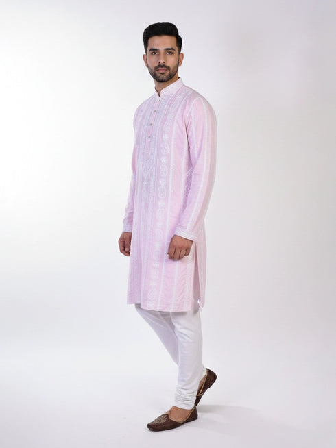 Man wearing a pink chikankari kurta with white churidar pants and brown embellished juttis.