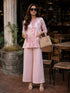 Woman wearing a pink floral print cotton kurta and matching pants, sitting at a table.